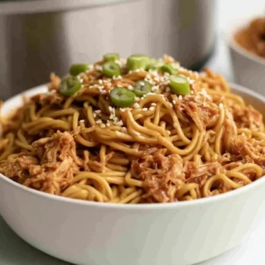 Crockpot Honey Garlic Chicken Noodles served in a bowl with fresh herbs.