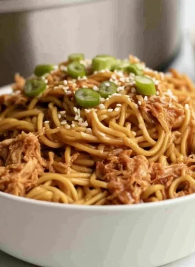Crockpot Honey Garlic Chicken Noodles served in a bowl with fresh herbs.