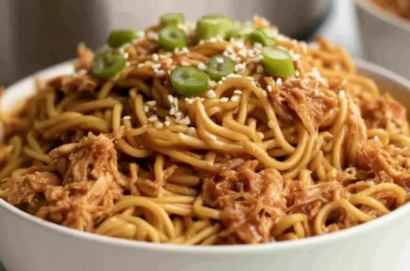 Crockpot Honey Garlic Chicken Noodles served in a bowl with fresh herbs.