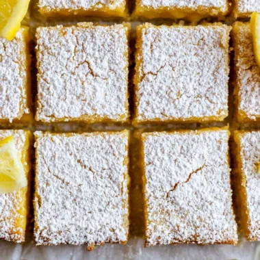 Cozy lemon bars drizzled with powdered sugar, a sweet citrus delight.