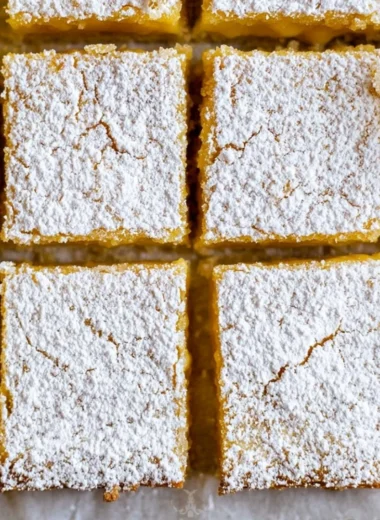 Cozy lemon bars drizzled with powdered sugar, a sweet citrus delight.