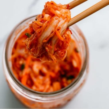 A bowl of vibrant homemade kimchi, showcasing fresh ingredients and spicy seasoning.