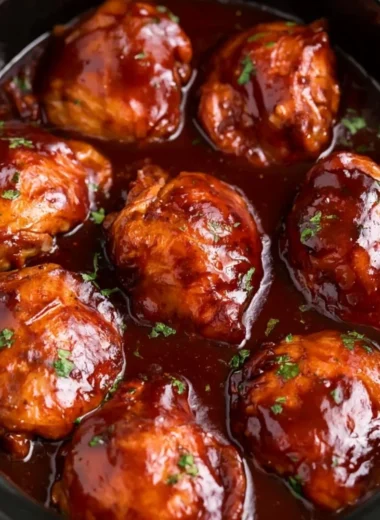 Slow Cooker BBQ Chicken Thighs served with sauce and garnished herbs