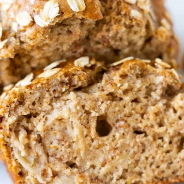 Freshly baked banana oatmeal bread with ripe bananas and oats on a wooden table.