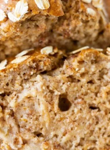 Freshly baked banana oatmeal bread with ripe bananas and oats on a wooden table.