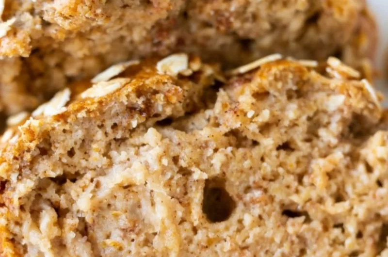 Freshly baked banana oatmeal bread with ripe bananas and oats on a wooden table.